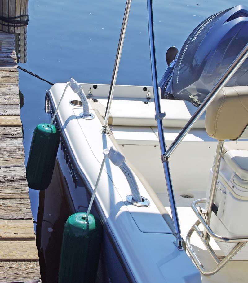 A white boat is docked at a dock with green fenders