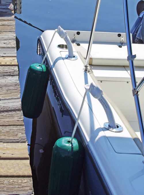 a boat is docked at a dock with a green fender