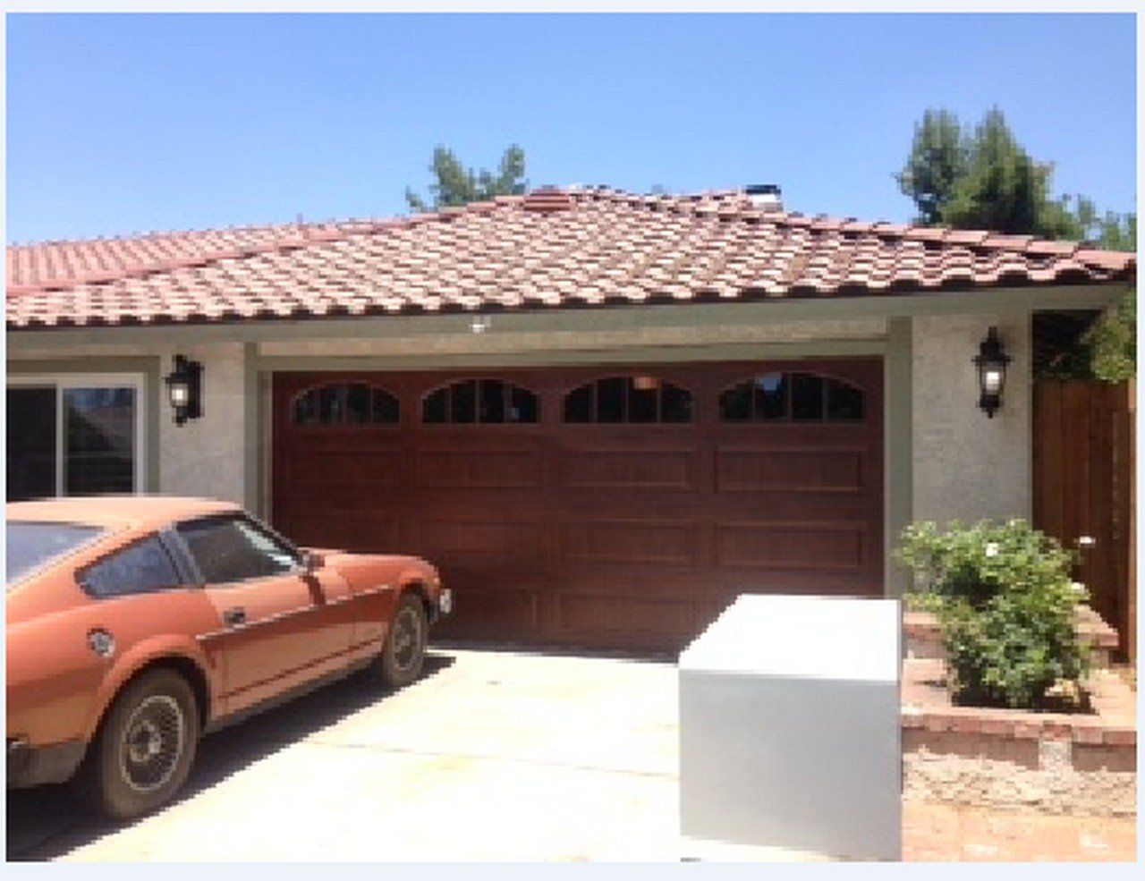 A car is parked in front of a house with a red garage door in Yucaipa
