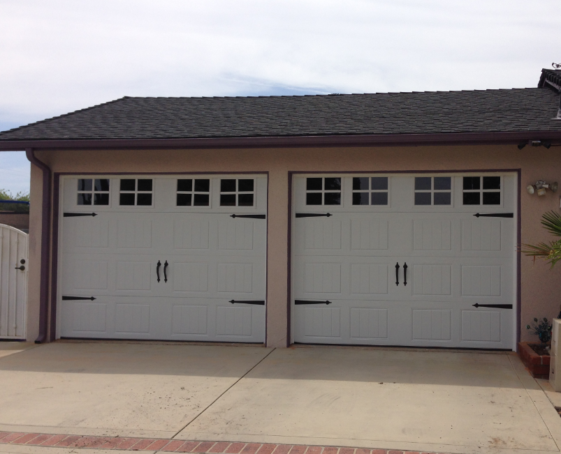 A house with two white garage doors and a black roof
