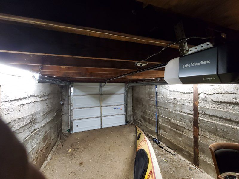 A garage with a kayak in it and a garage door open.