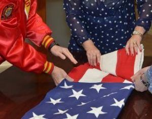 Hands folding an American flag on a table