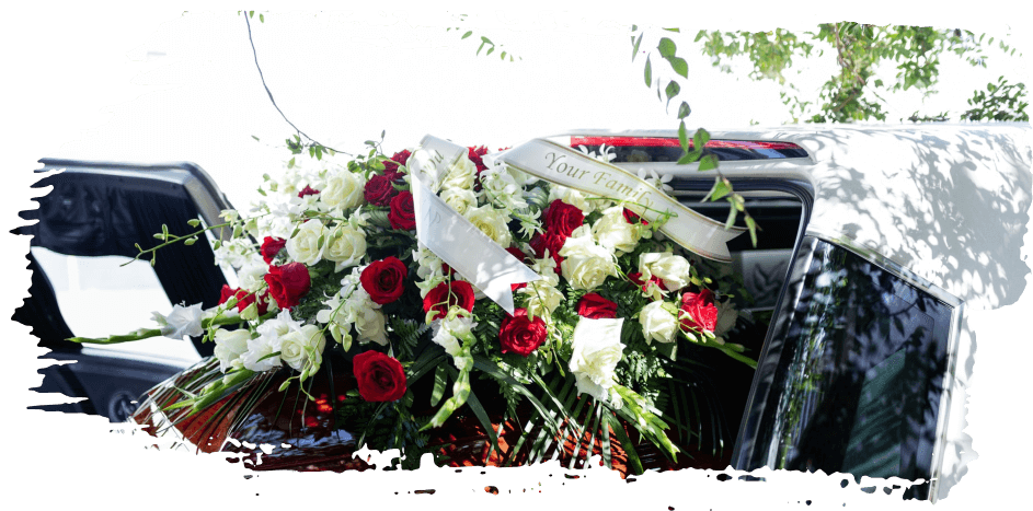 White and red funeral flowers arranged on a black hearse hood outdoors