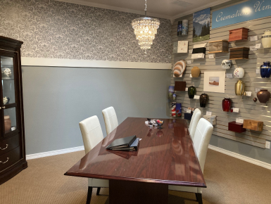 Dining room with wooden table, white chairs, patterned wallpaper, and decorative wall shelves