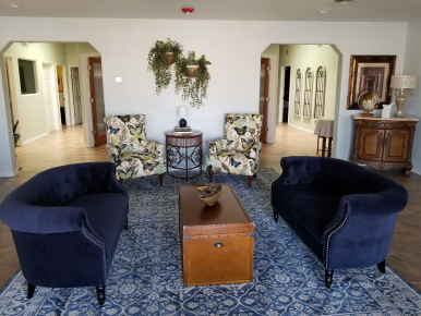 Bright living room with navy chairs, patterned loveseat, and wooden coffee table on blue rug