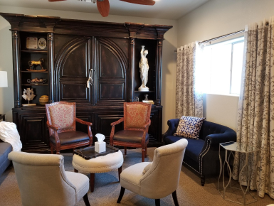 Elegant living room with dark wood cabinet, white chairs, and patterned window curtains