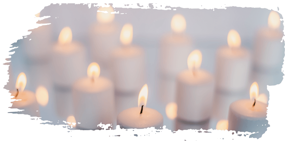Lit white candles glowing softly against a blurred light background
