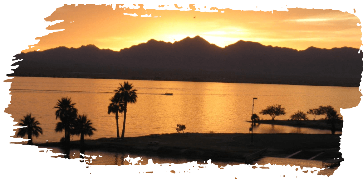 Orange sunset over a calm tropical sea with silhouetted mountains and palm trees