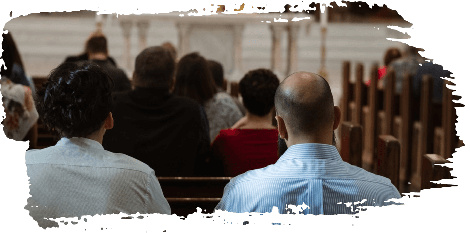 People seated in rows at an indoor event, seen from behind in a softly blurred hall.