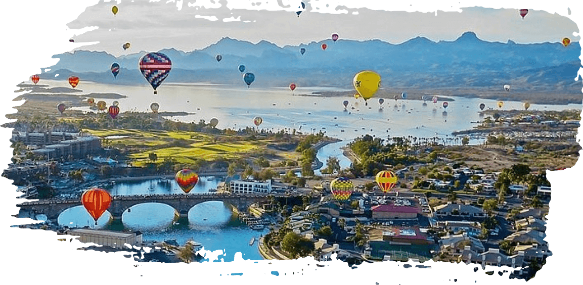 Hot air balloons over a river and bridge with mountains in the distance at sunrise