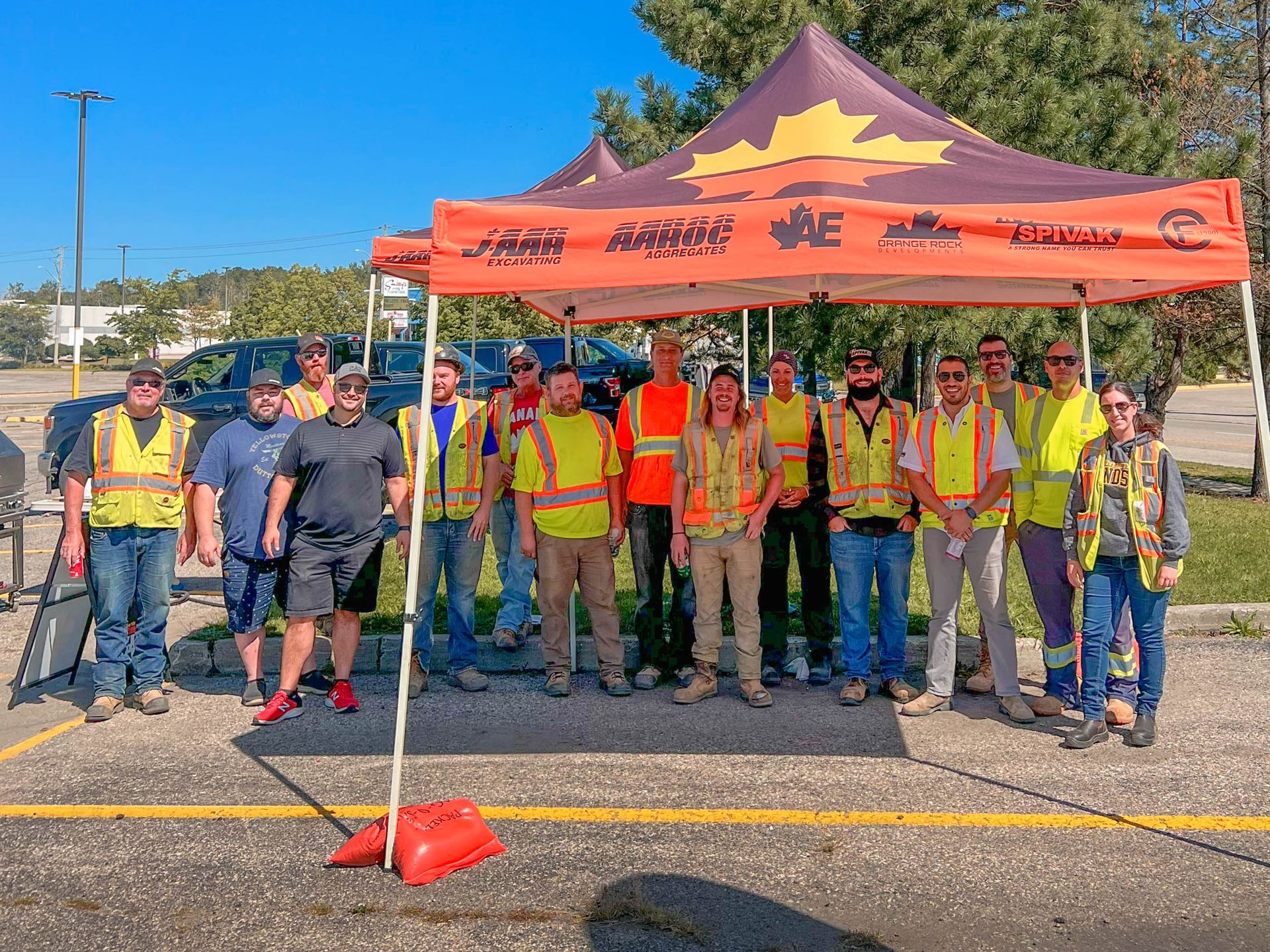a group of construction workers are posing for a picture under a tent .