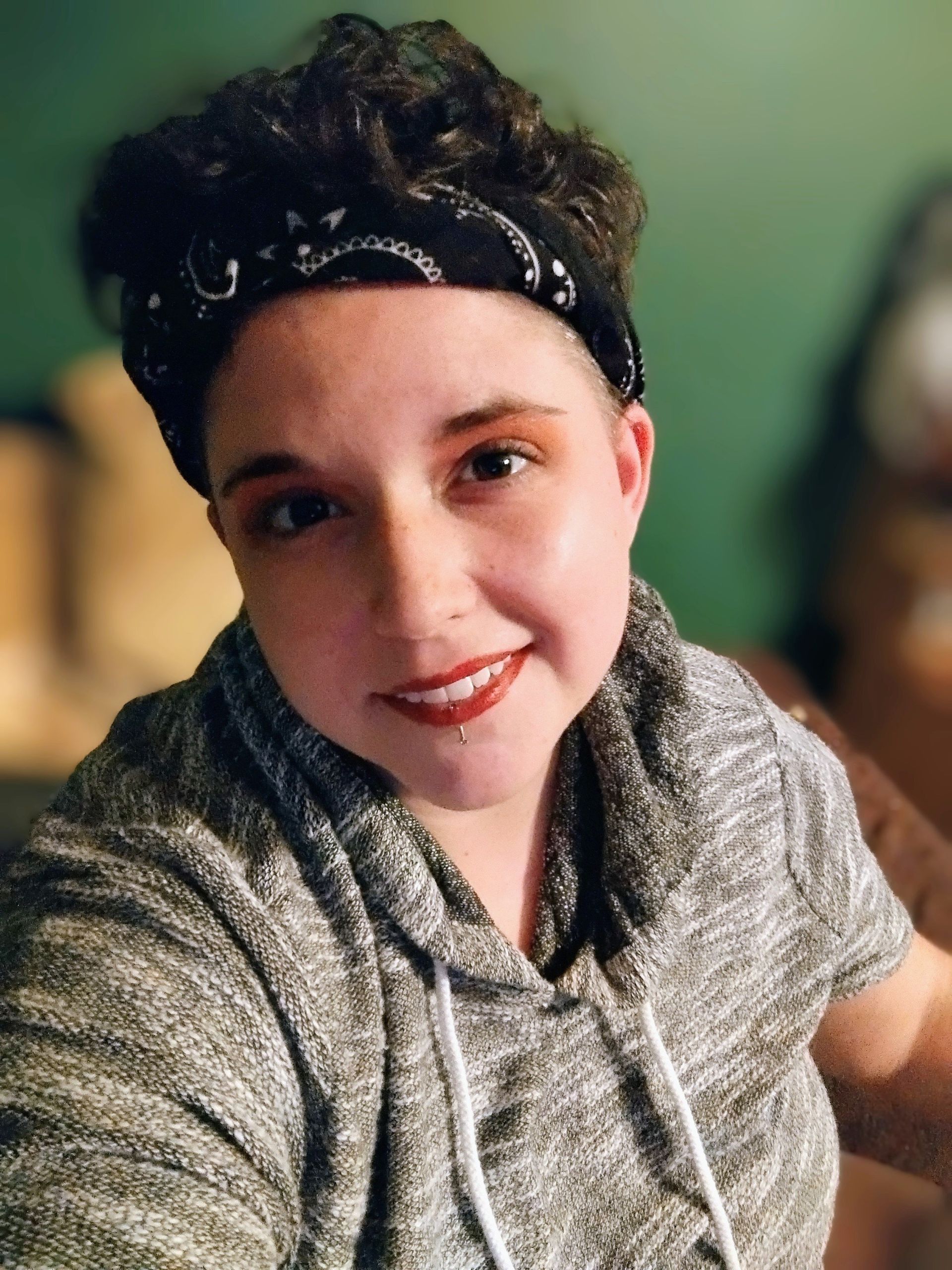 A young woman wearing a headband and a hoodie is smiling for the camera.