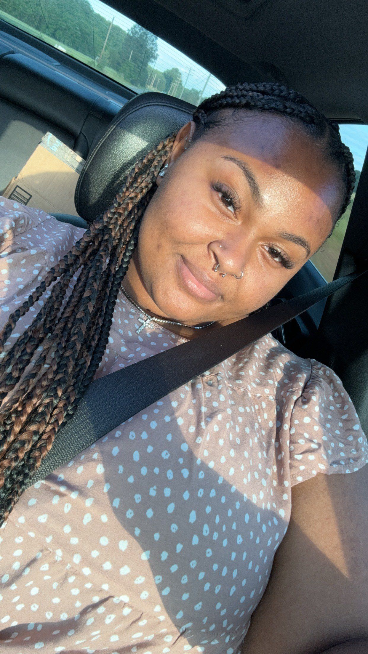 A woman is sitting in the back seat of a car wearing a seat belt.