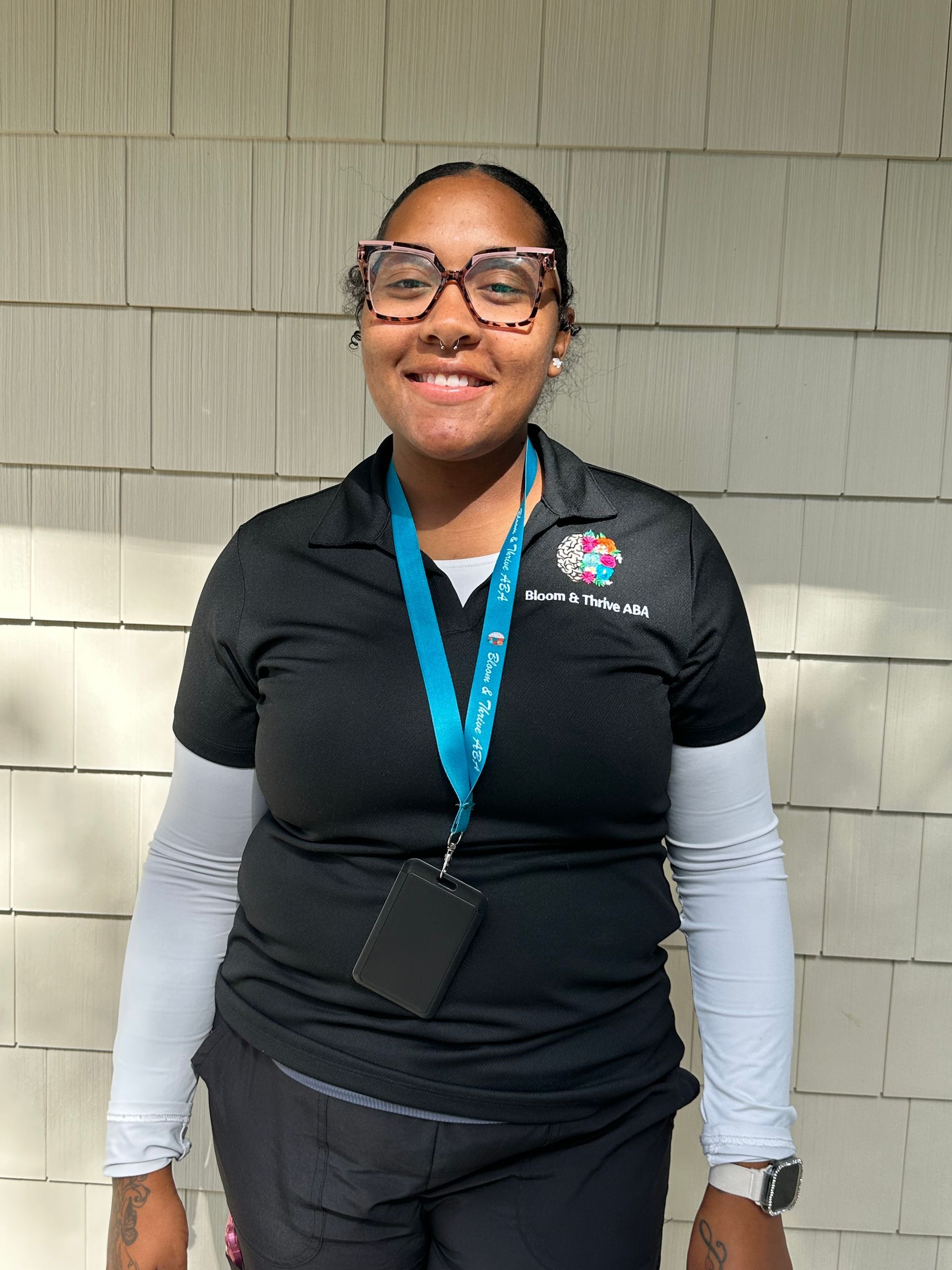 A woman with long black hair is wearing a blue shirt and smiling.