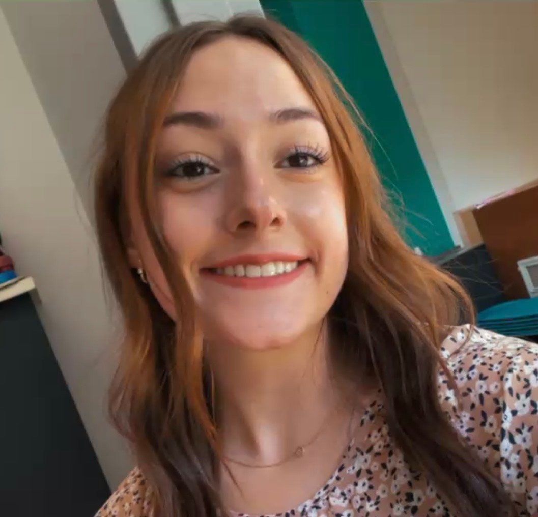 A woman with long brown hair is smiling for the camera