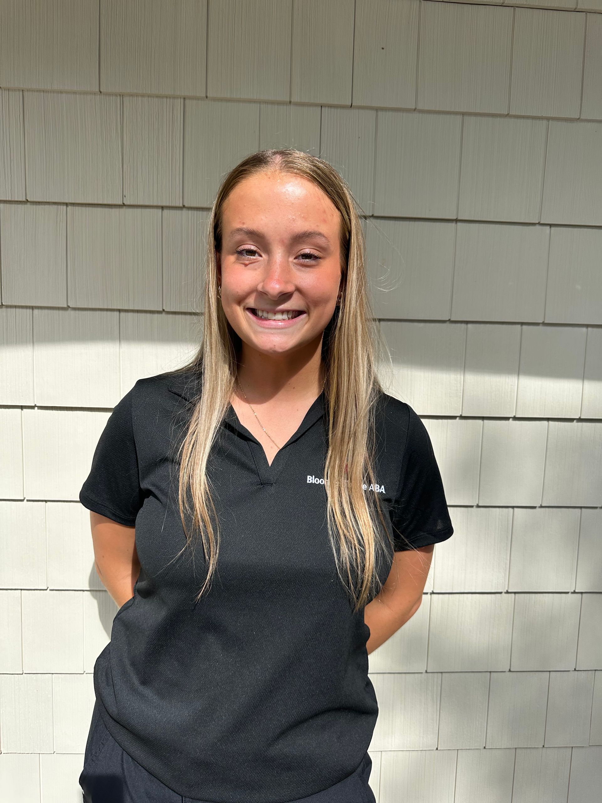 A young woman wearing a black strapless top and earrings is smiling for the camera.