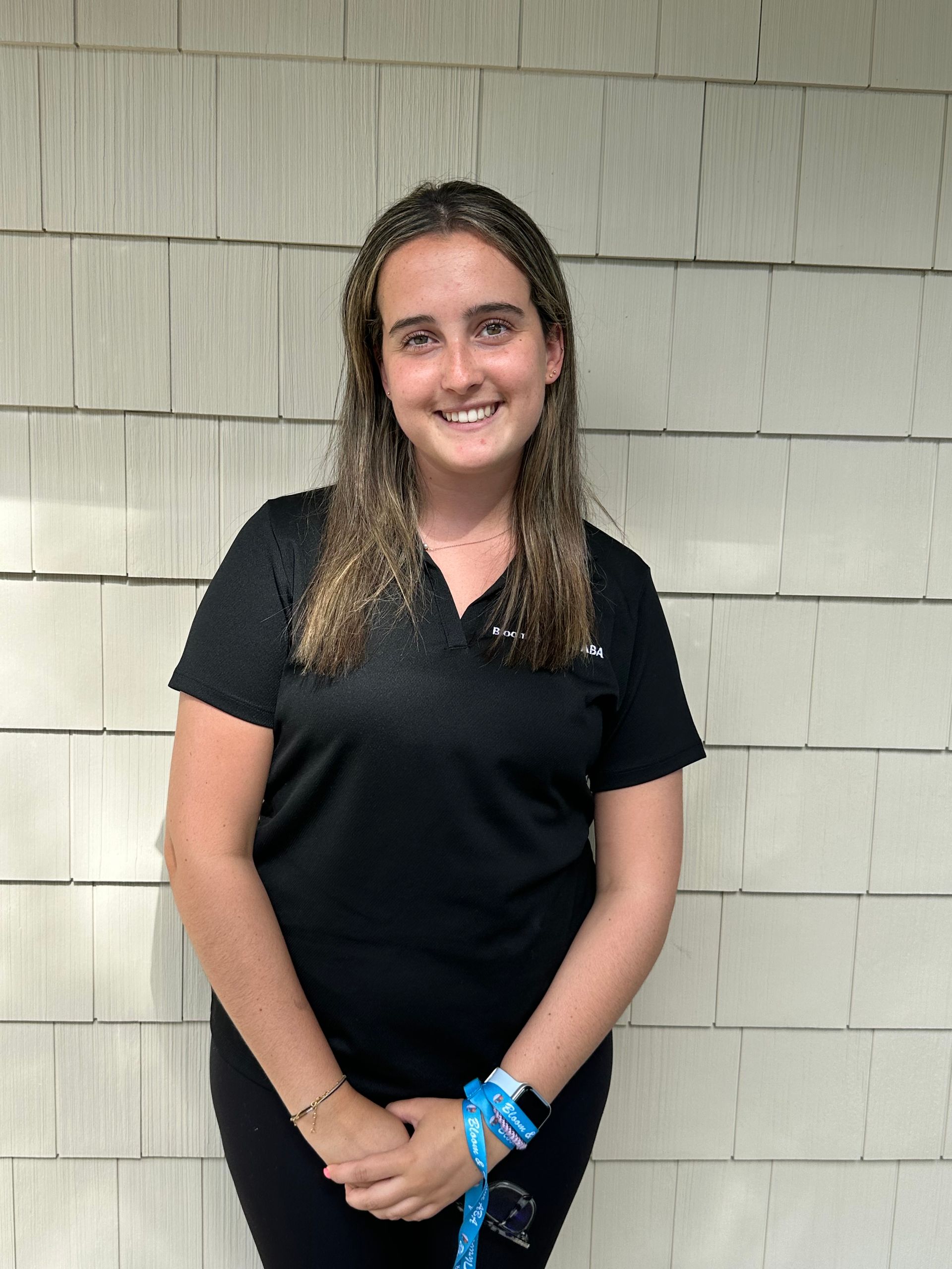 A young woman wearing glasses and a green sweater is smiling for the camera.