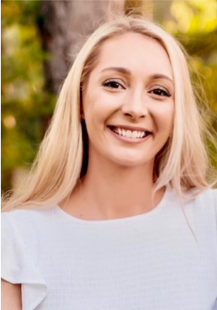 A woman in a colorful floral shirt is smiling for the camera.