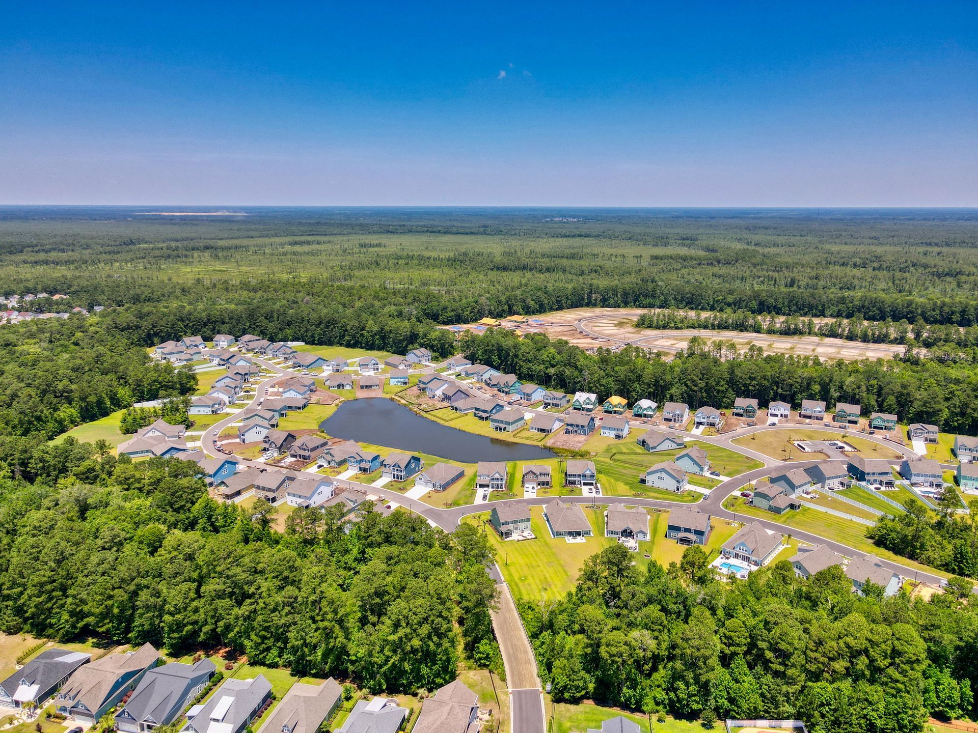 An aerial view of a residential area surrounded by trees and a lake.