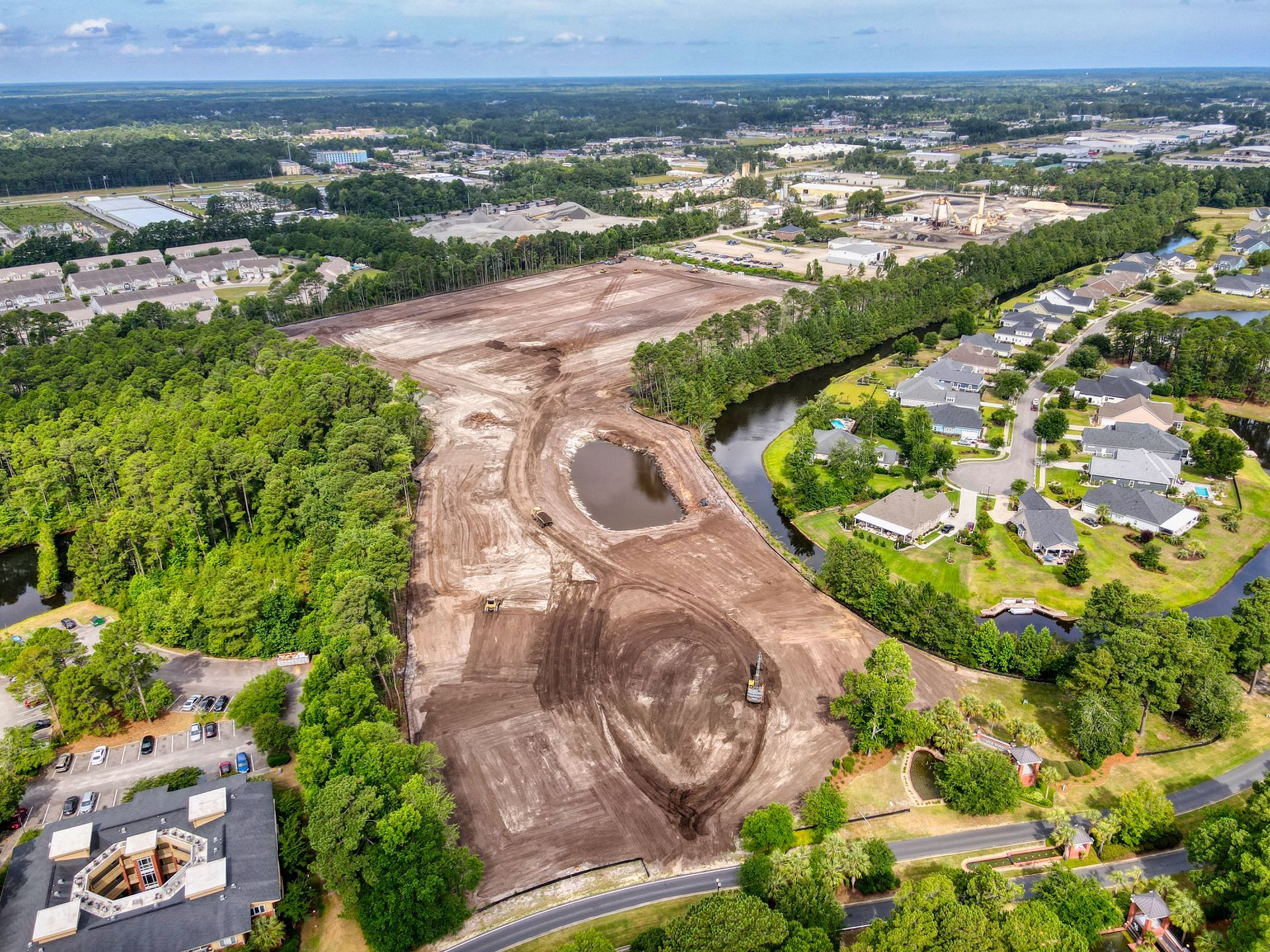 An aerial view of a residential area surrounded by trees and a river.