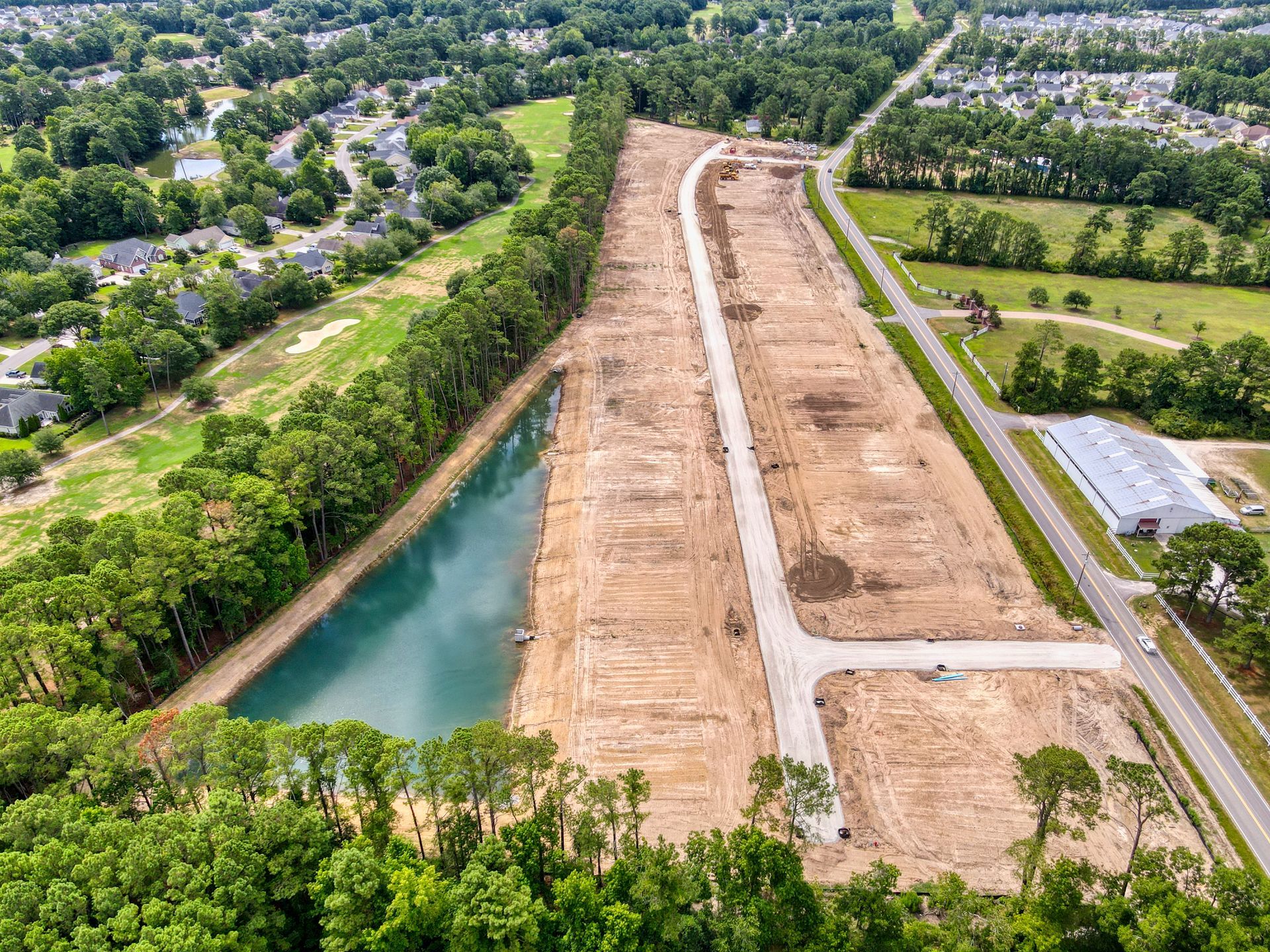 An aerial view of a construction site with a lake in the middle of it.