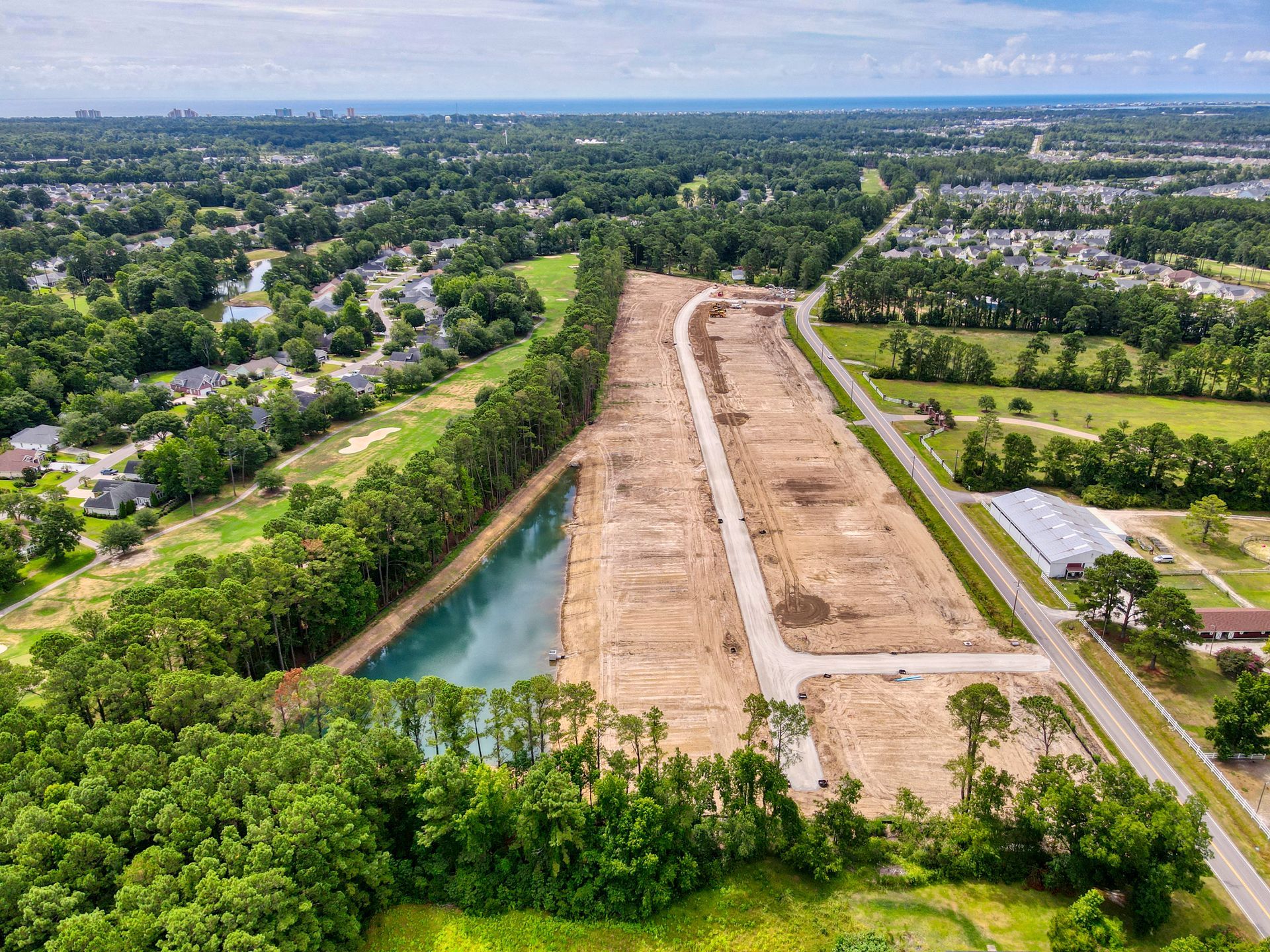 An aerial view of a construction site with a pond in the middle of it.