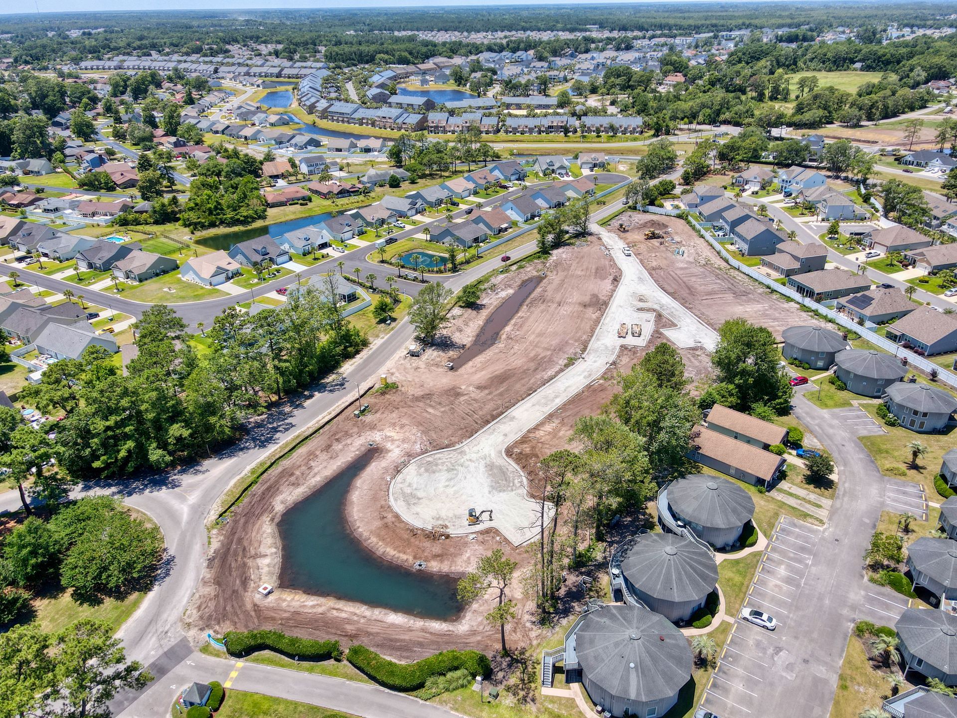 An aerial view of a residential area with a pond in the middle of it.