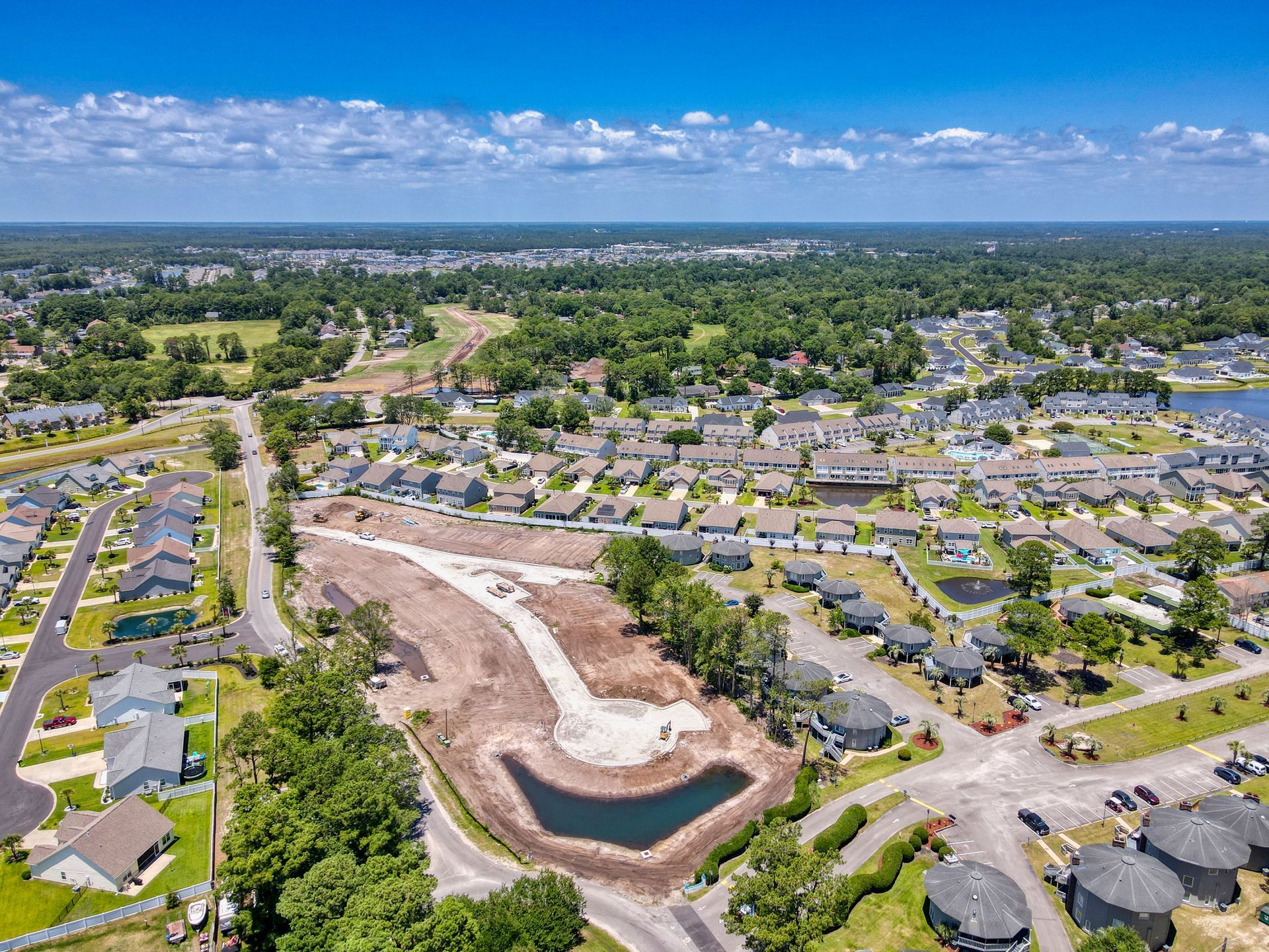 An aerial view of a residential area with a pond in the middle of it.