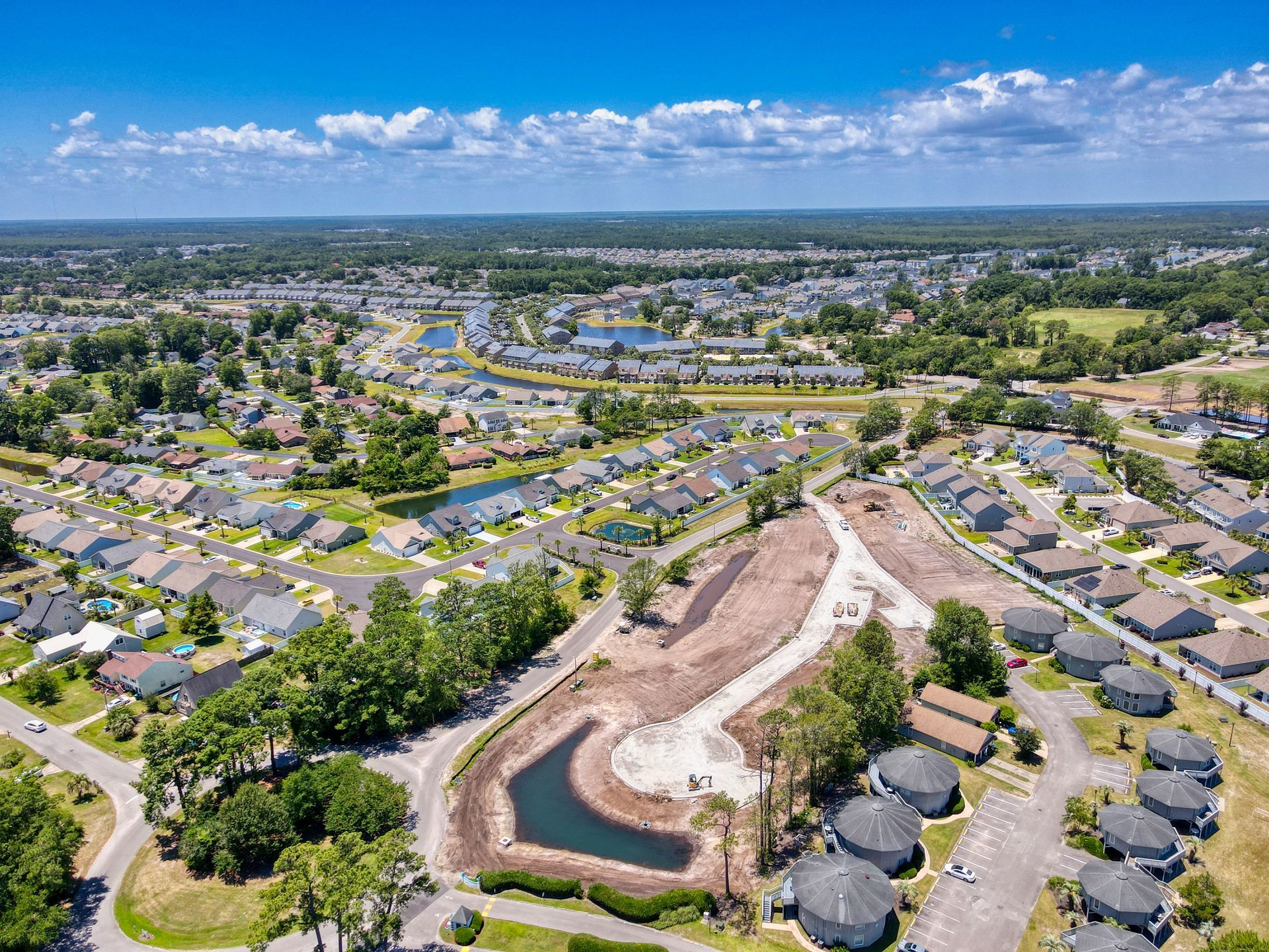 An aerial view of a residential area with a pond in the middle of it.