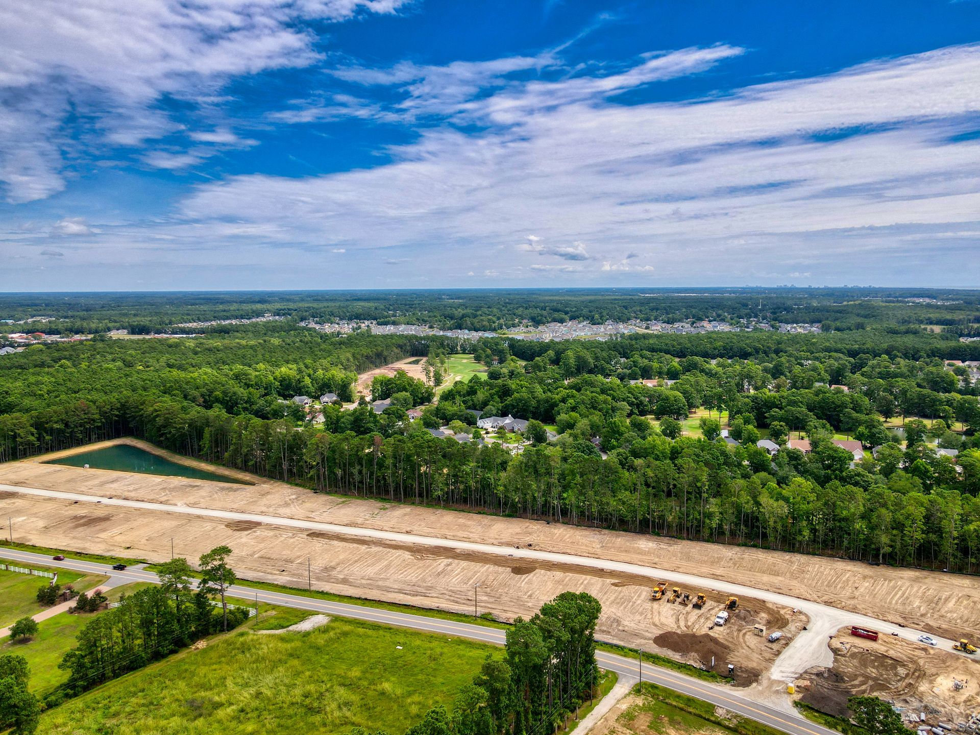 An aerial view of a residential area with lots of trees and a road.