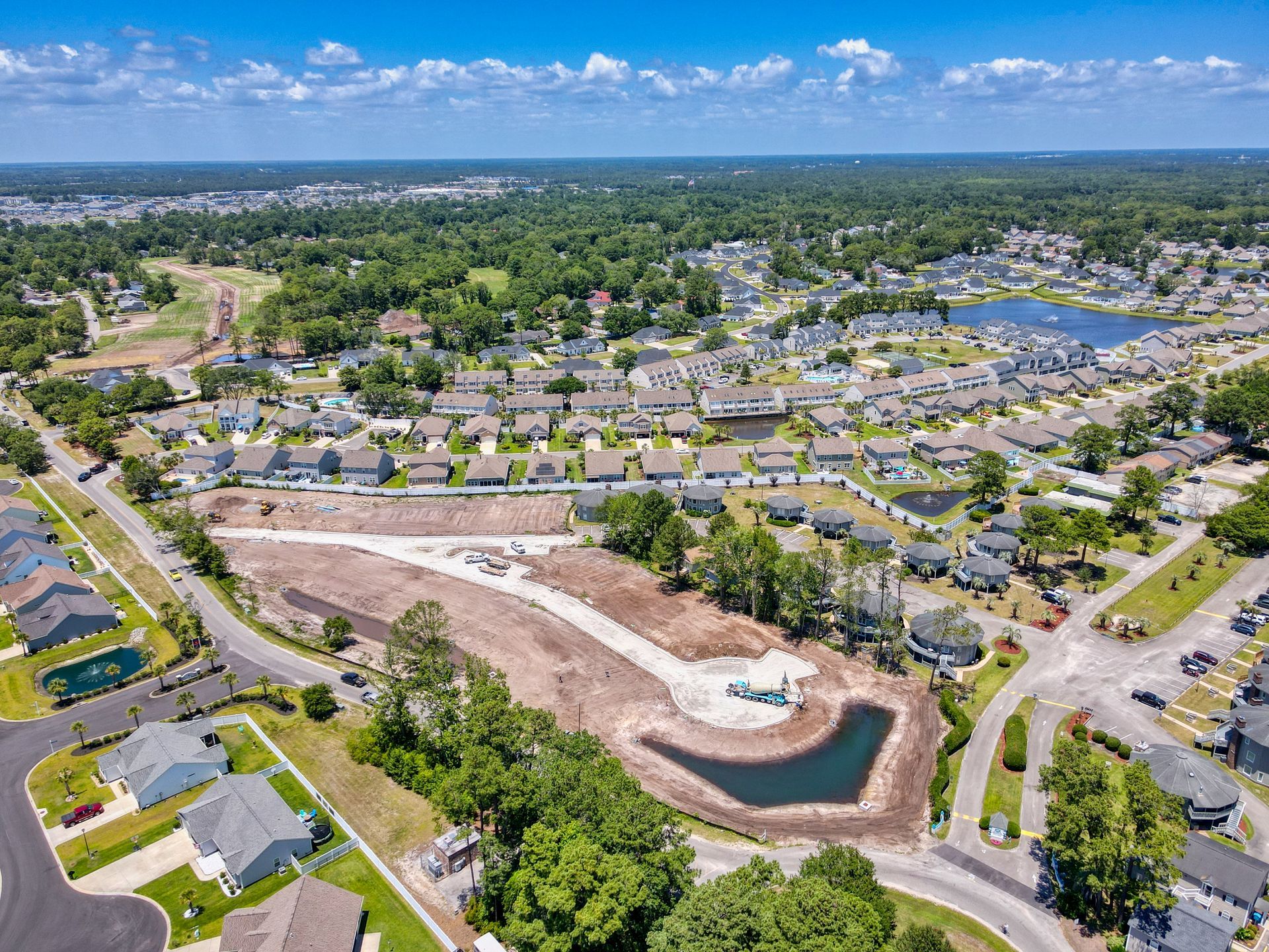 An aerial view of a residential area with a pond in the middle of it.