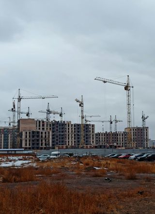 A large construction site with a lot of cranes and buildings in the background.