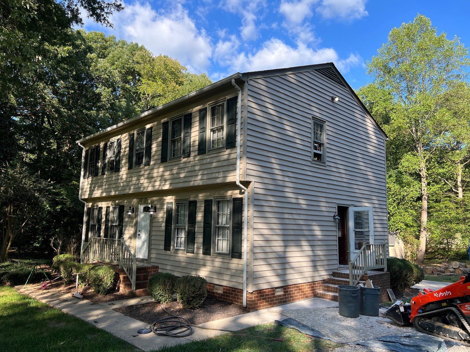 A house with a tractor parked in front of it.