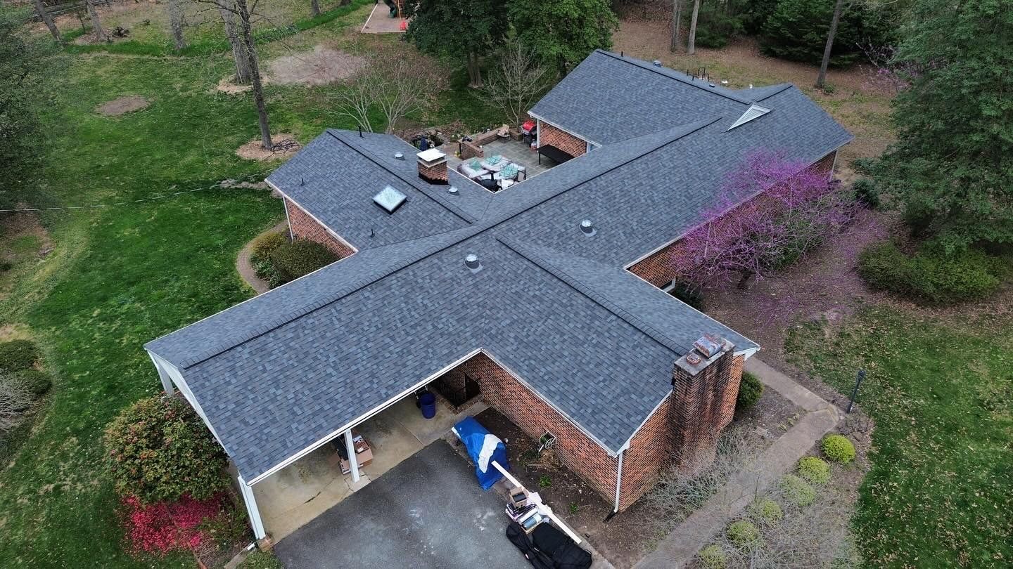 An aerial view of a brick house with a new roof.