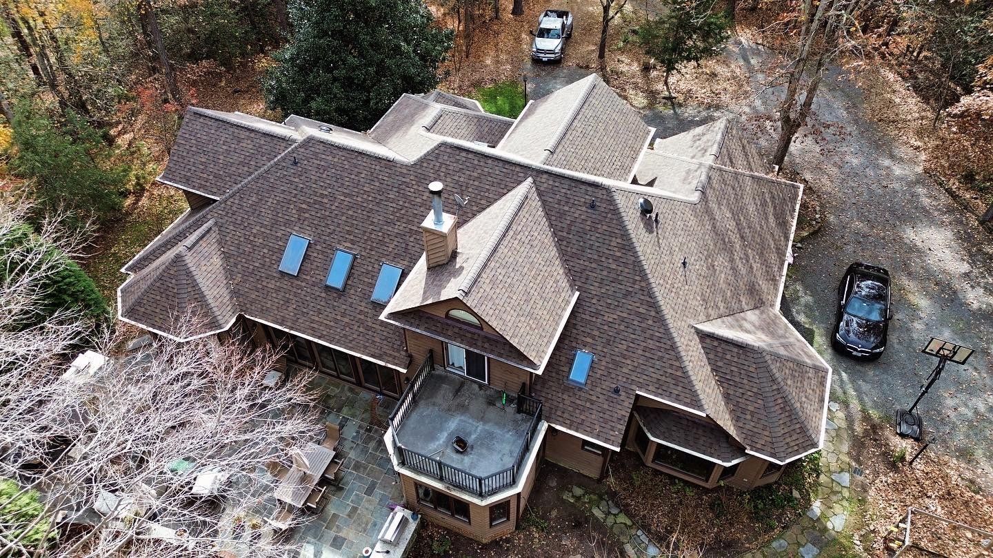 An aerial view of a large house in the middle of a forest.
