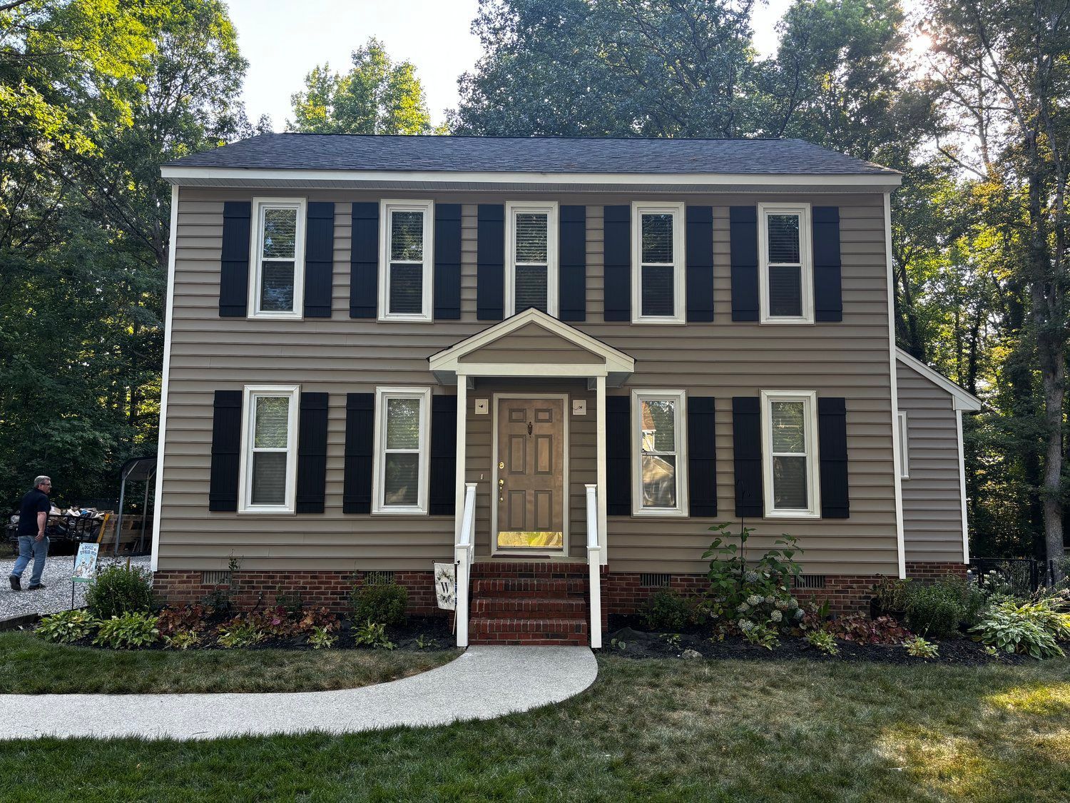 A large house with black shutters and a walkway in front of it