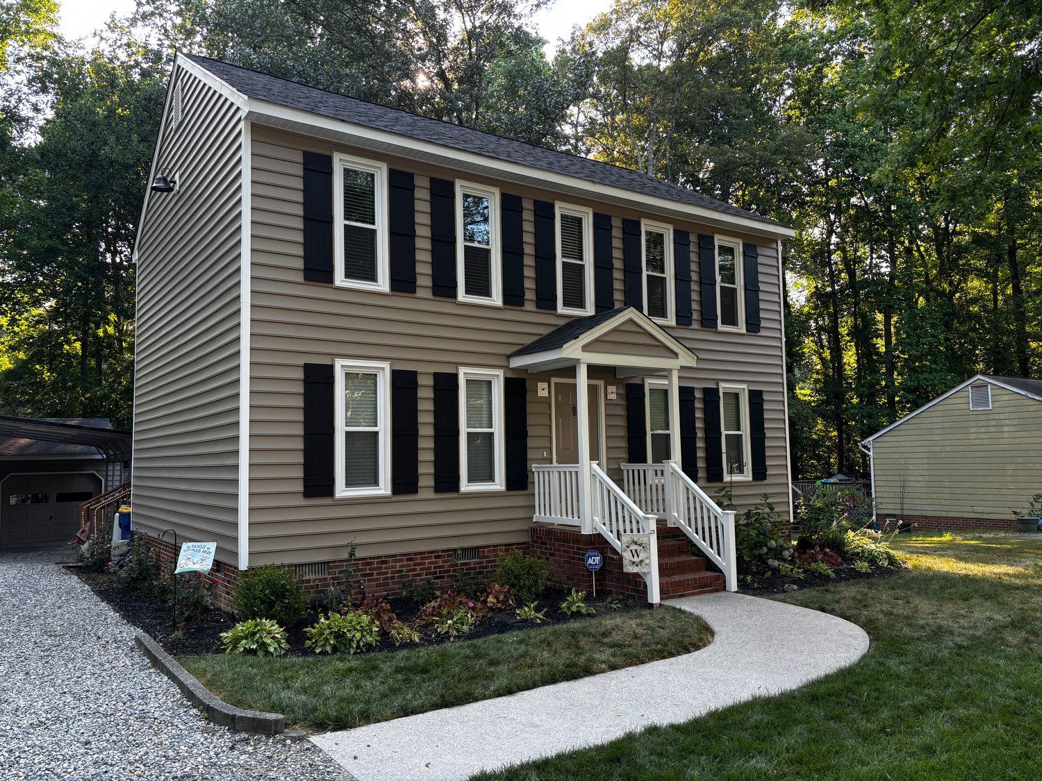 A large house with black shutters and a walkway in front of it.