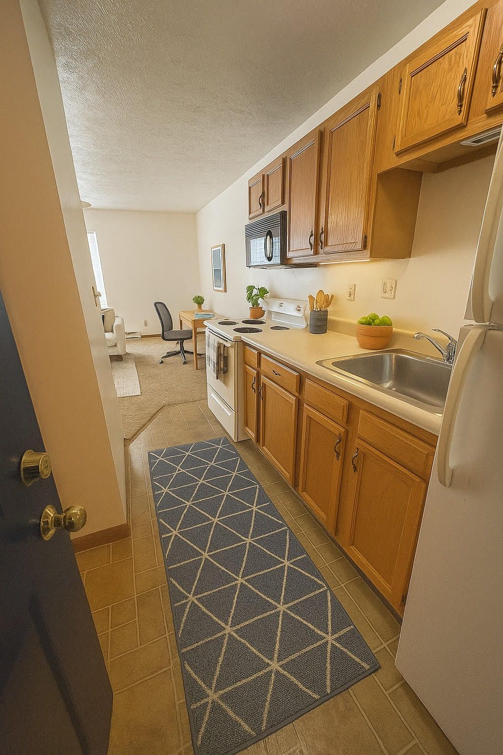 A kitchen with wooden cabinets , a refrigerator , a sink , and a rug.