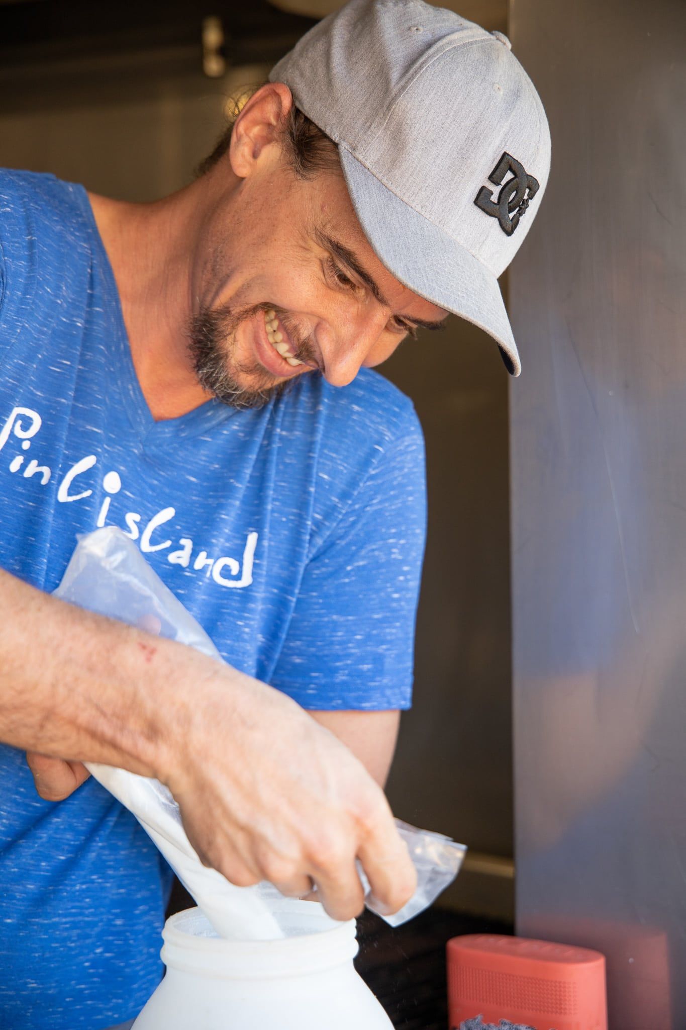 A man wearing a hat and a blue shirt is making ice cream.