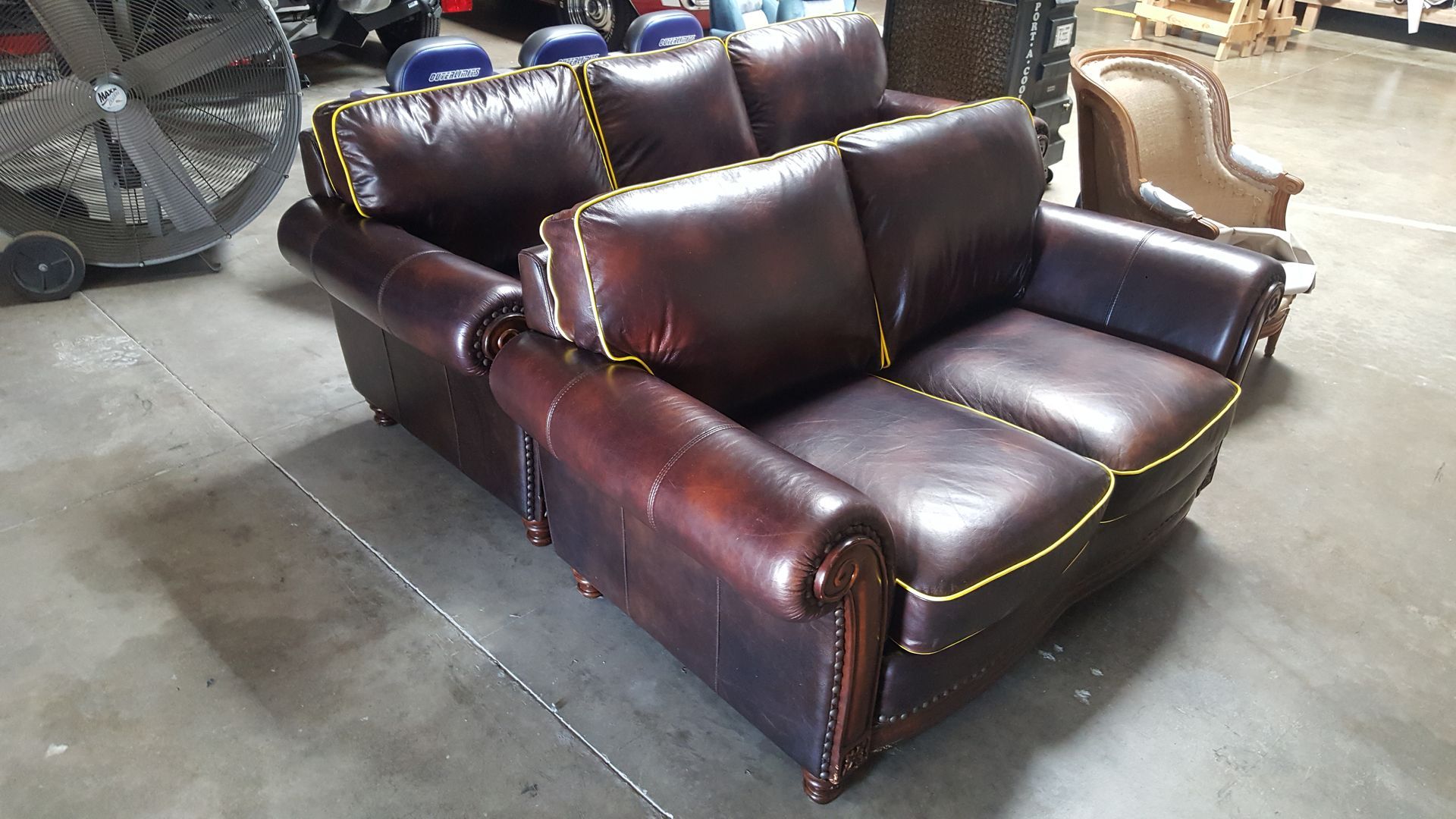 A brown leather couch is sitting in a warehouse.