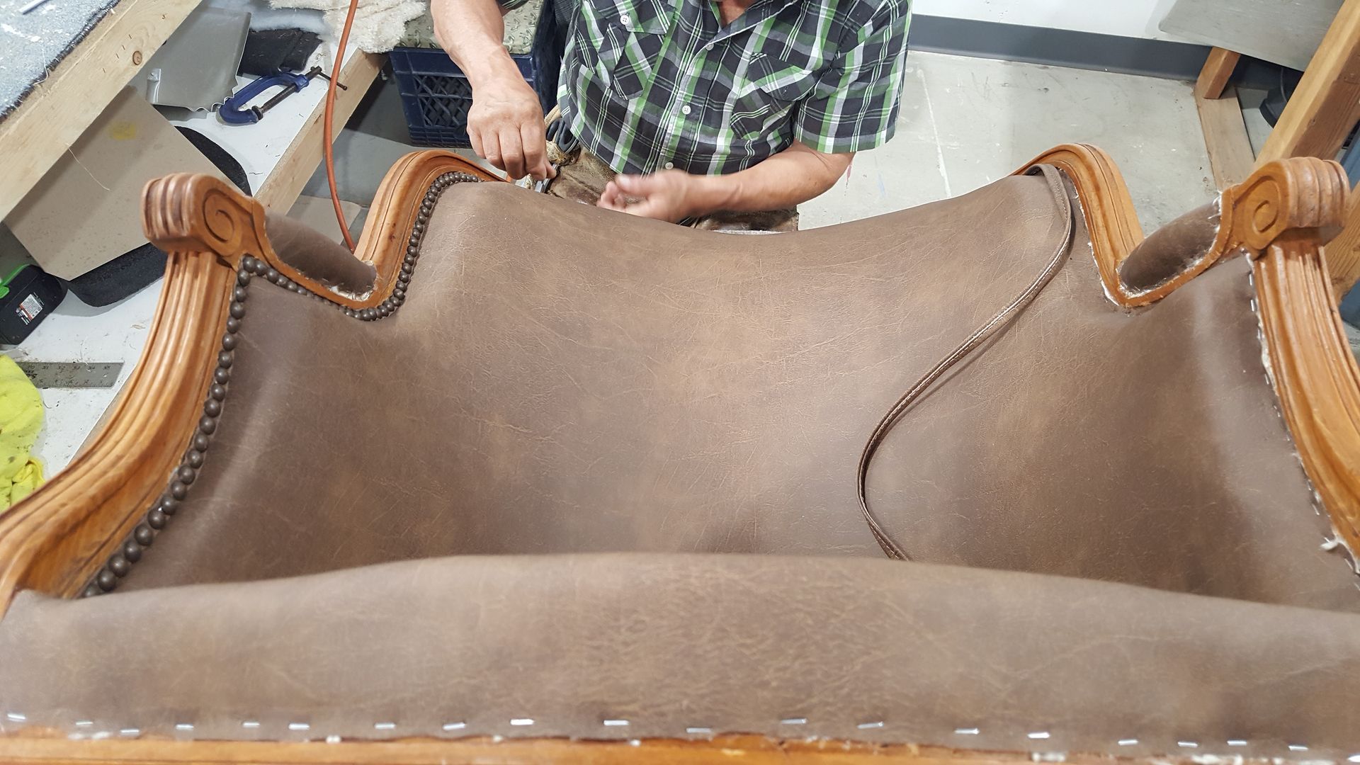 A man is working on the back of a chair.