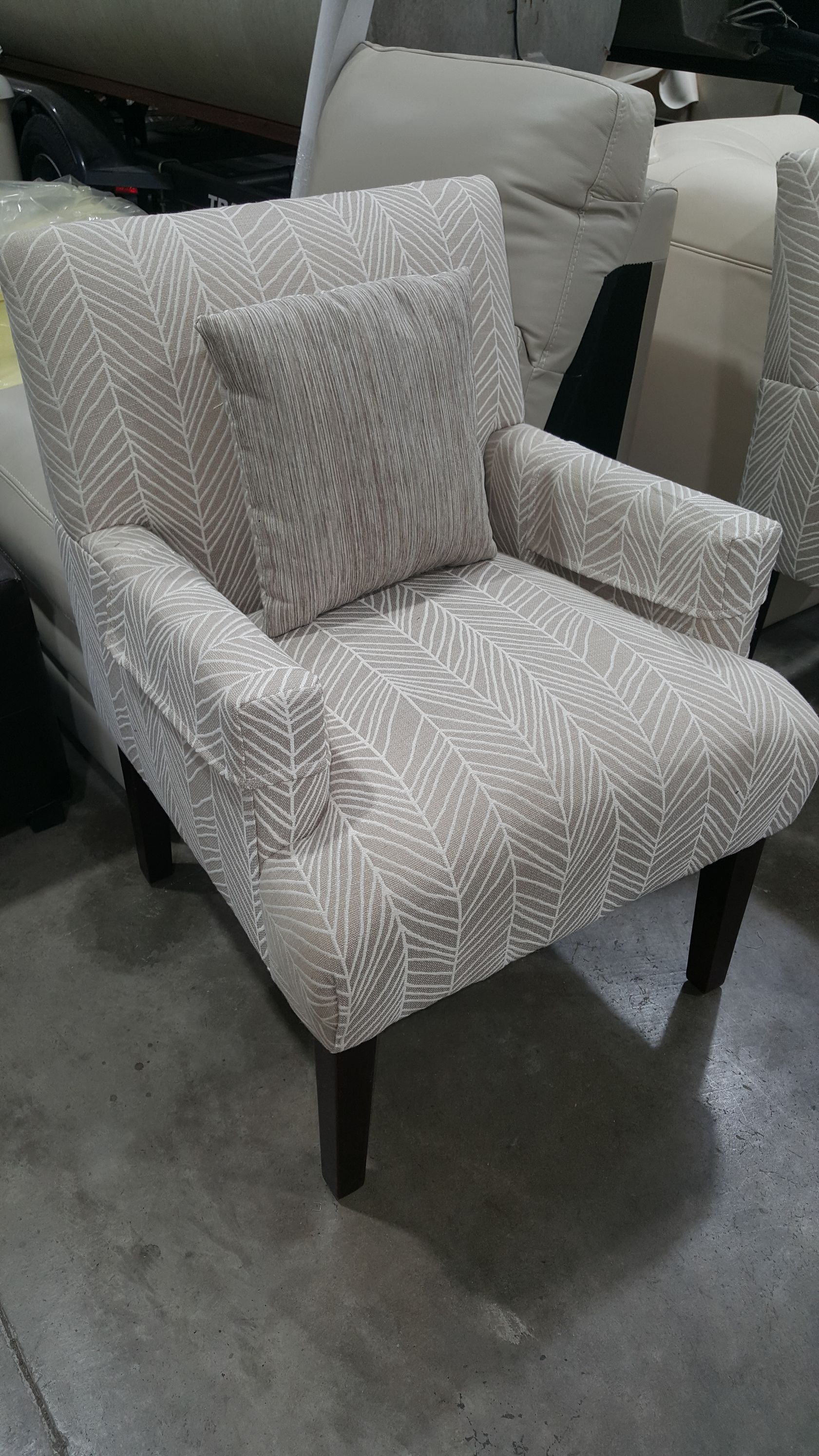 A chair with a pillow on it is sitting on a concrete floor.