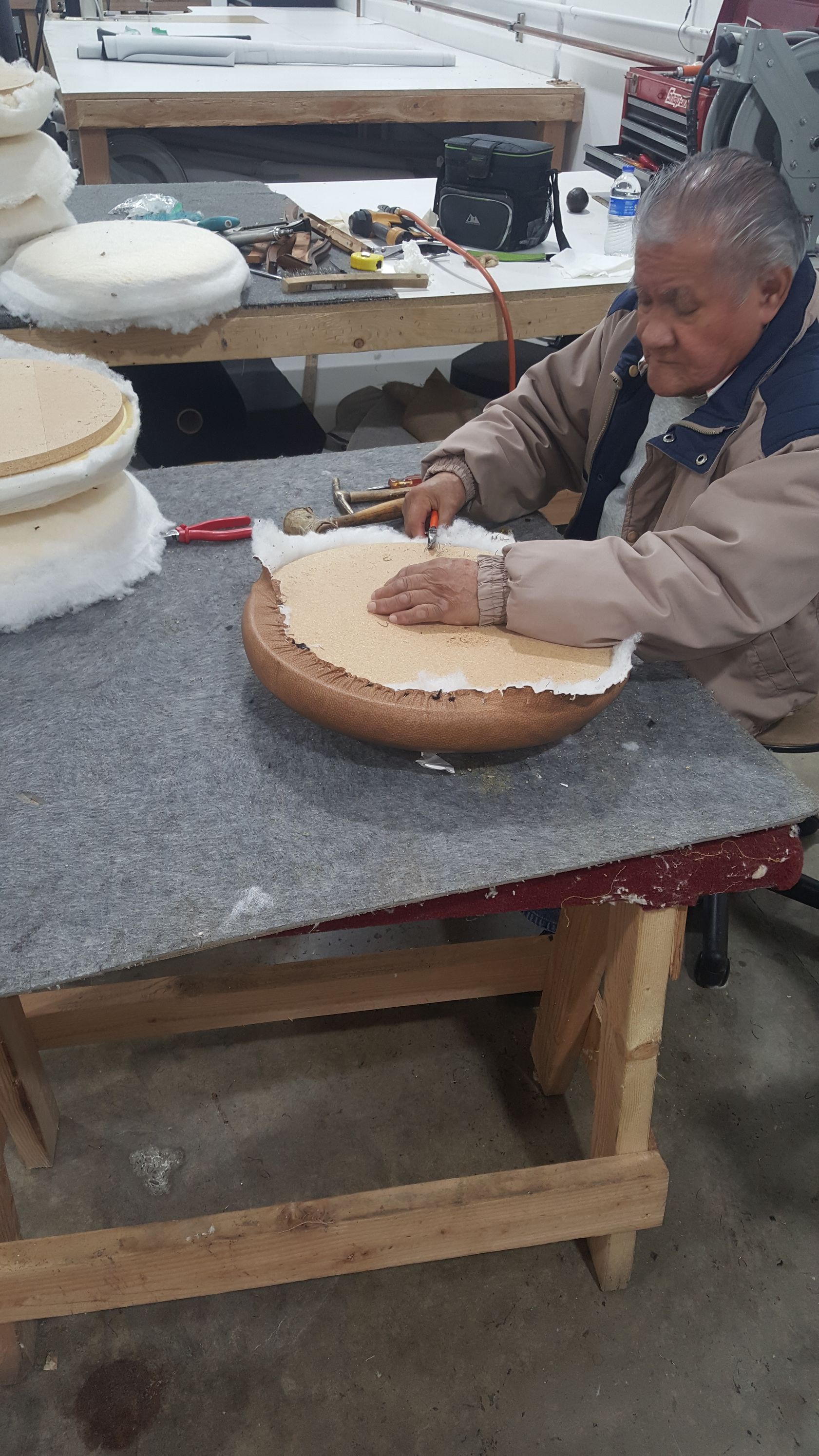 A man is sitting at a table working on a piece of wood.