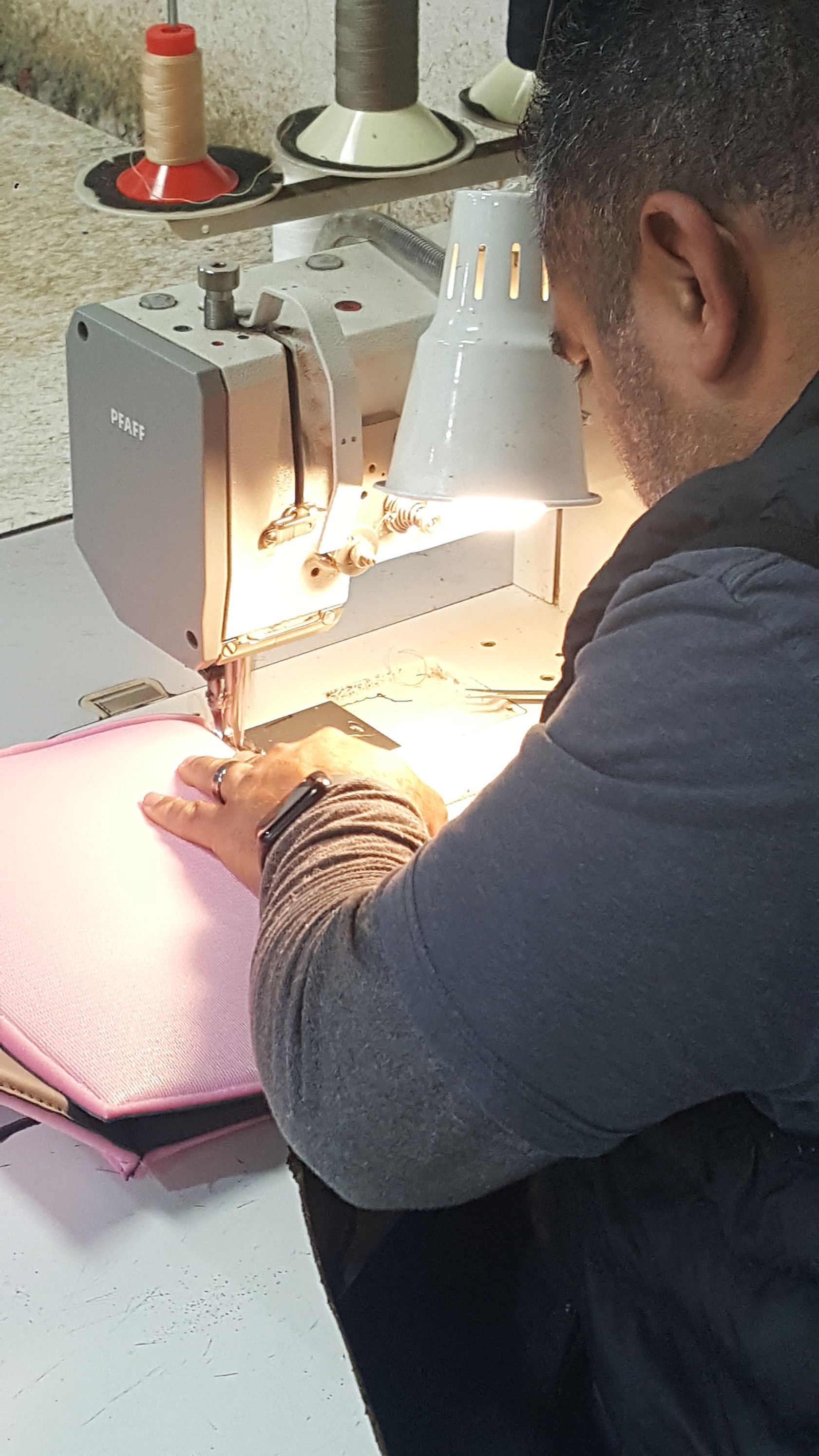 A man is sitting in front of a sewing machine.