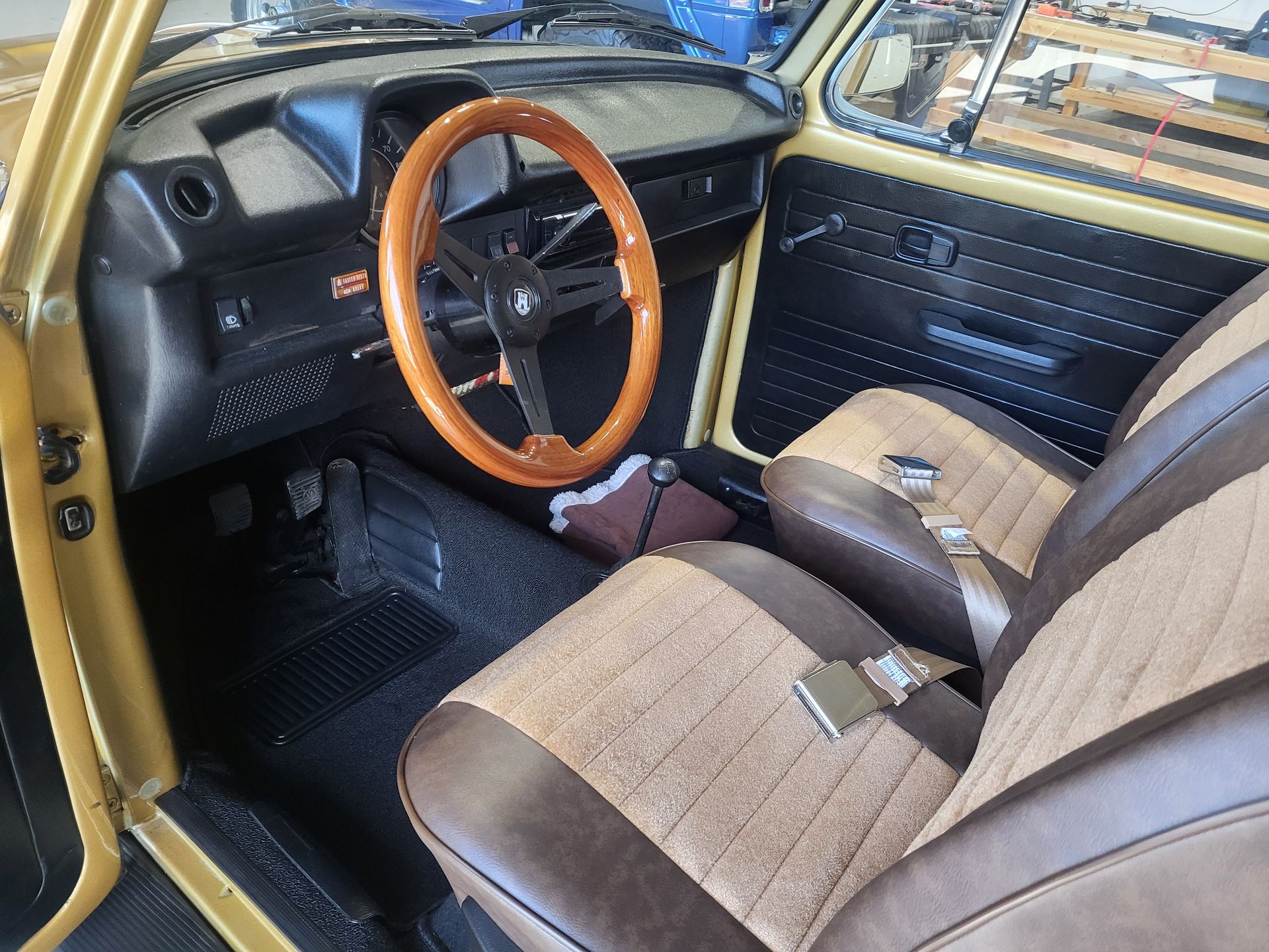 The interior of a yellow car with brown seats and a wooden steering wheel