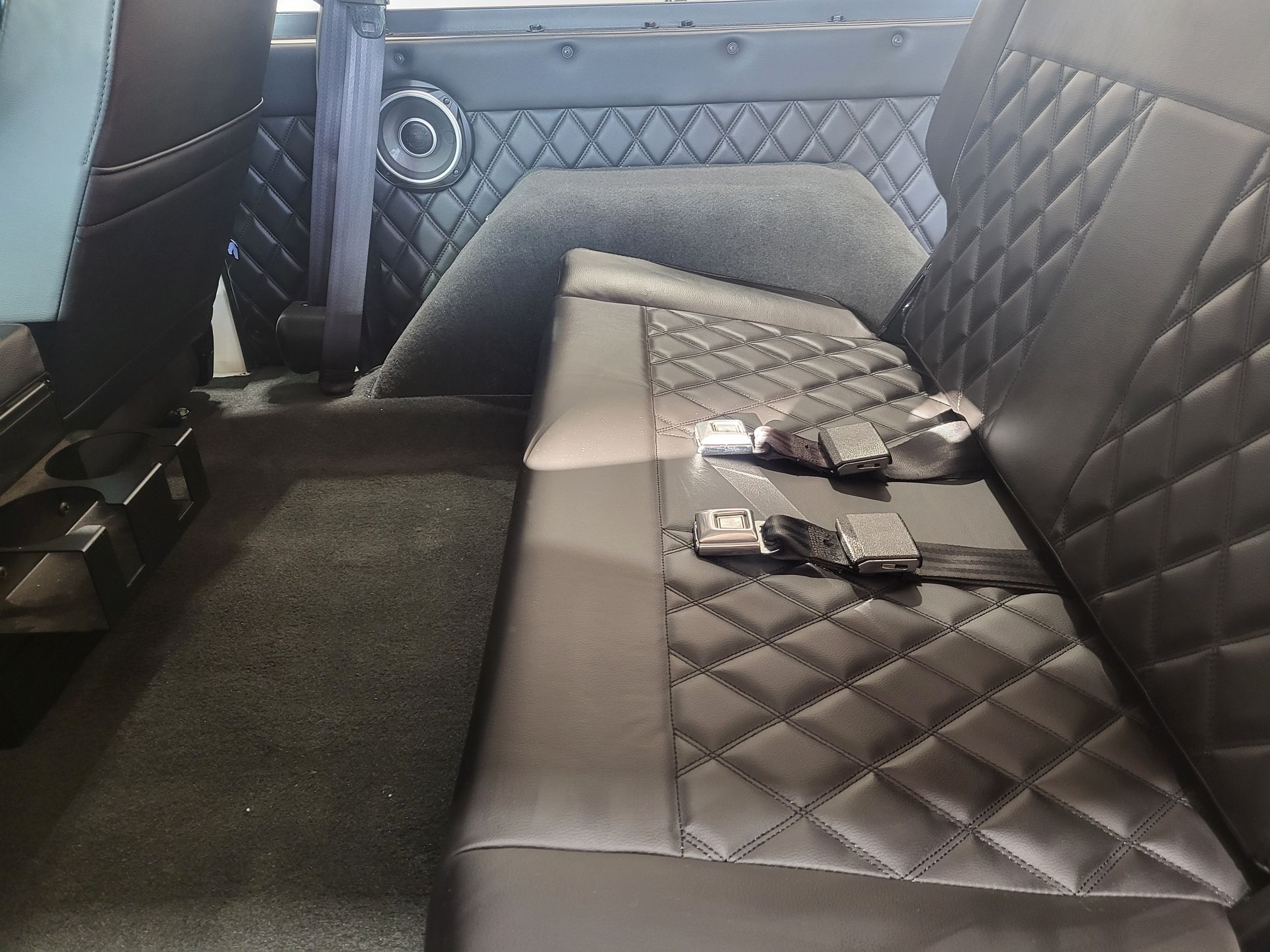 The back seat of a car with seat belts on it