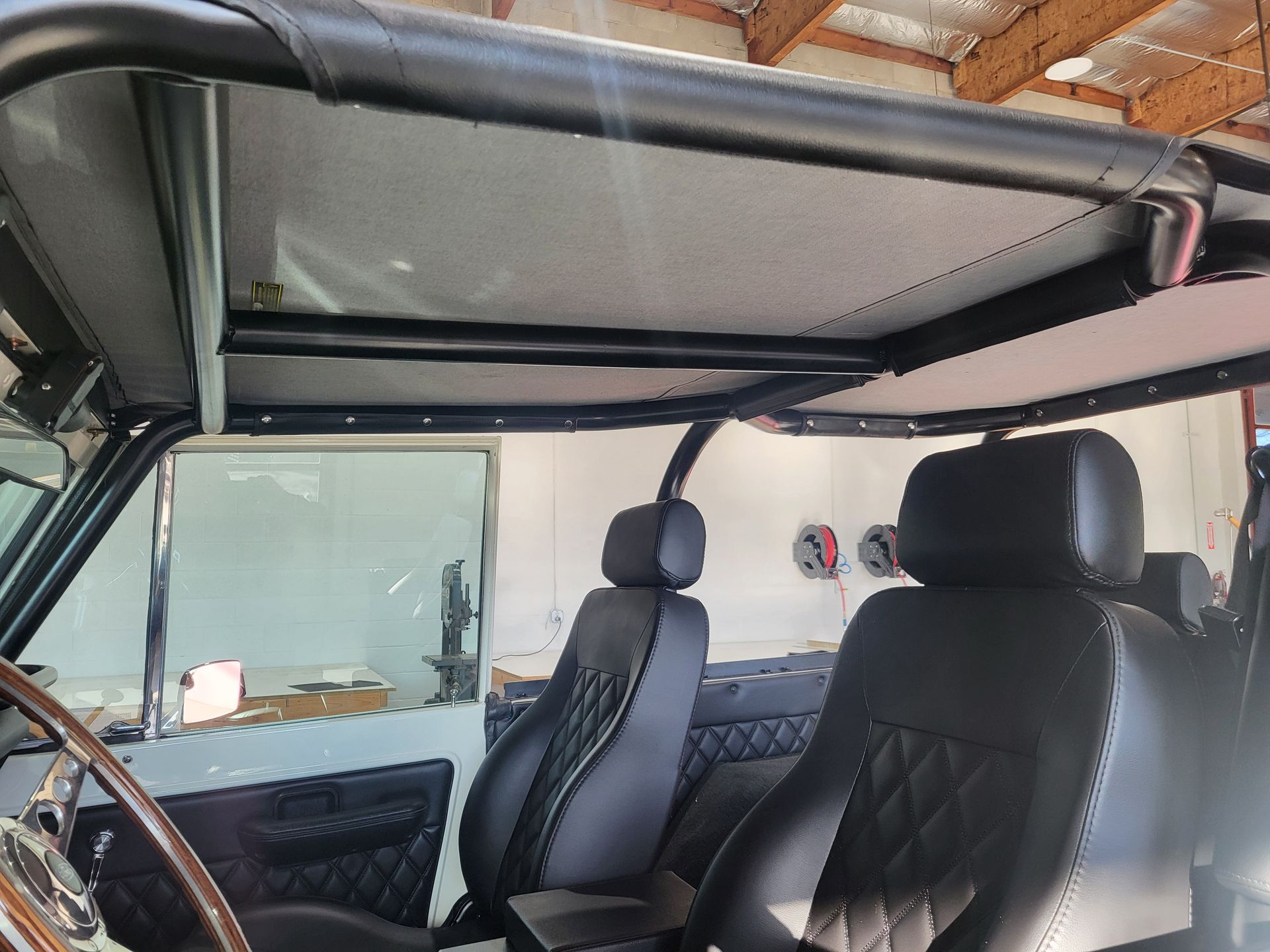 The inside of a jeep with black seats and a roof rack.
