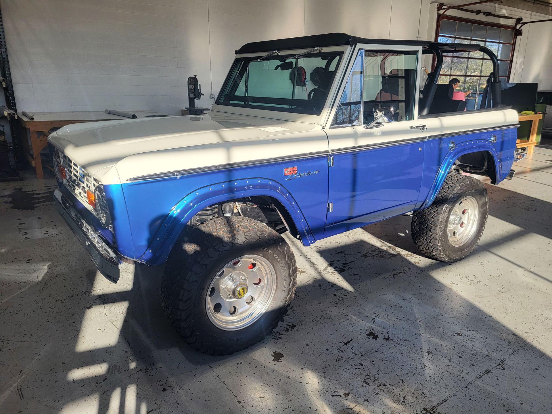 A blue and white ford bronco is parked in a garage.