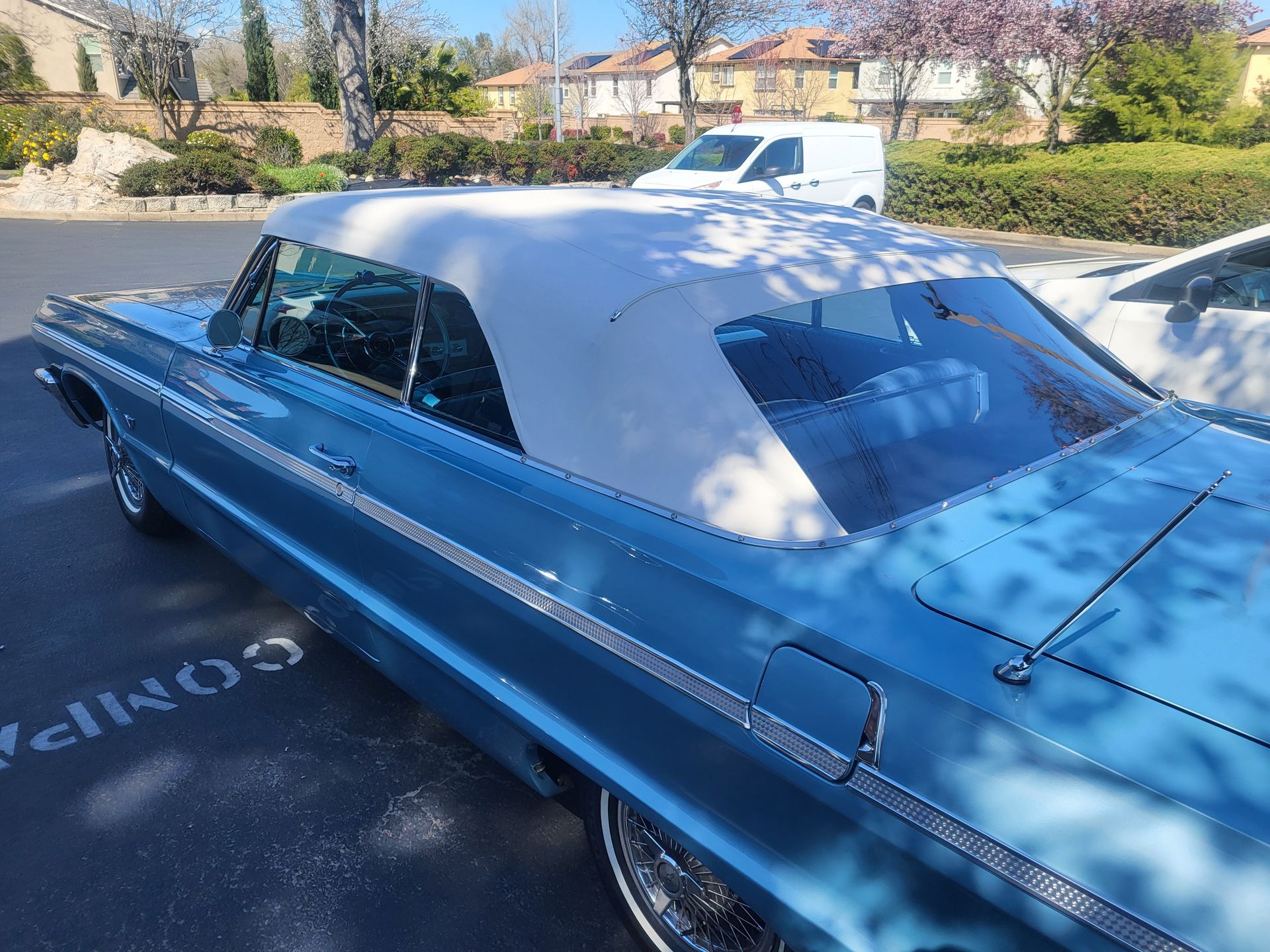 A blue car with a white top is parked in a parking lot.
