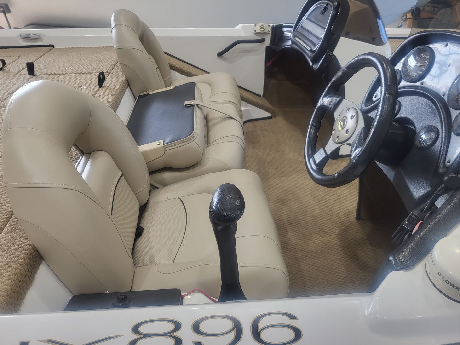 The inside of a boat with a steering wheel and seats.